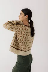Sweater de punto color beige con diseño de rombos marrones, cuello polo con botones y mangas largas abullonadas.