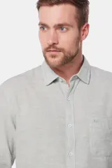 Camisa de lino color beige, de manga larga, con cuello clásico y bolsillo en el pecho.