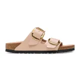 Sandalia de dos correas color beige brillante con hebillas doradas y suela de corcho.