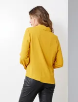 Camisa amarilla de crepe con cuello con solapa, escote en V y abertura central con botones. Delantera fruncida.