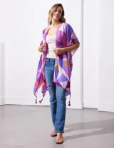 Kimono tejido con estampado geométrico en tonos violeta, rosa, naranja y blanco. Tiene mangas amplias estilo japonés y terminación con borlas en el ruedo.