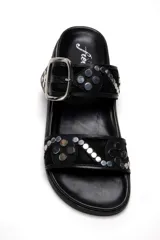 Sandalias negras de cuero con dos tiras, una con hebilla plateada y otra con tachas plateadas.