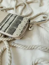 Billetera grande de cuero con estampado de reptil en tonos beige y gris. Tiene cierre metálico, forro interior y múltiples compartimentos. Incluye moneda colgante plateada con el logo de la marca.