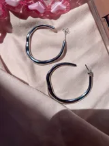 Aros de metal con forma irregular en tono plateado, elaborados en aleación.