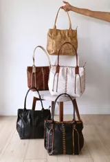 Bolso tipo tote de cuero color camel, con costuras a la vista y tiras de ajuste laterales.