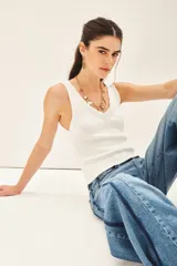 Musculosa blanca tejida en hilado de algodón, con escote en V pronunciado y calce al cuerpo.