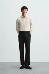 Camisa color beige de corte slim fit, confeccionada en tejido elástico con cuello italiano abierto, manga larga con puños abotonados y cierre frontal con botones.