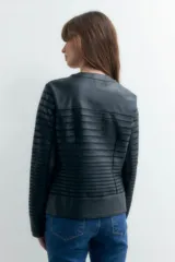 Chaqueta negra de eco cuero con detalles de tul en mangas y hombros, cierre frontal con cremallera dorada y corte ajustado.