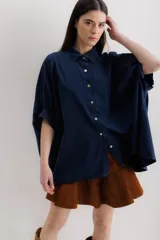 Camisa azul de mangas cortas abullonadas, con cuello clásico y cierre frontal con botones.