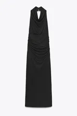 Vestido largo negro con cuello halter y escote fluido, hombros descubiertos, detalle de drapeado en los laterales, forro interior a tono, bajo con abertura en la espalda y cierre lateral con cremallera oculta y botones en el cuello.