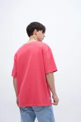 Remera roja de algodón con calce oversize, teñida en prenda con arte en el pecho y bordado en la manga.