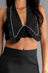 Top halter negro con cuello grande estilo solapa con borde de perlas sintéticas y cierre con botones en el frente.