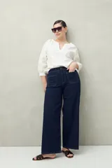 Pantalón de jean azul oscuro, de corte ancho y tiro alto, con bolsillos delanteros cuadrados y amplios.