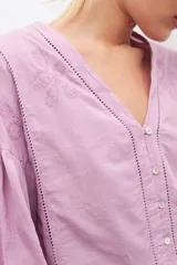 Blusa lila con bordados, de mangas largas abullonadas y cuello en V.
