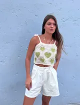 Top corto de crochet color crema con corazones verdes y tirantes finos con lazo.