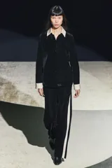 Camisa negra de terciopelo con cuello solapa, manga larga con puños en tejido color crema a contraste y bajo redondeado.