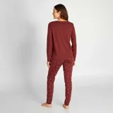 Conjunto de pijama de 2 piezas color burdeos, compuesto por una remera de manga larga con texto y pantalones ajustados con pequeños puntos.