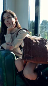 Mochila color topo agamuzada con detalle tramado al frente, apertura superior con cierre metálico, división al medio y bolsillos internos. Incluye correa corta de mano y correas regulables para colgar en la espalda.