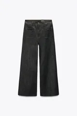 Pantalón de jean de tiro alto color negro con pierna ancha, bolsillos delanteros y traseros, y cierre frontal con cremallera y botón metálico.