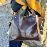 Cartera tote de cuero color marrón oscuro, con doble asa de hombro, cierre superior y bolsillo interno.