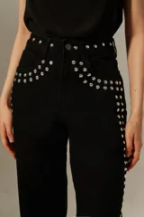 Pantalón negro de corte ancho con tachas plateadas en la cintura y laterales.