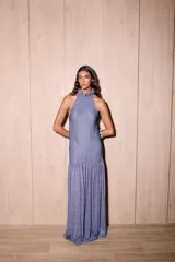 Vestido largo azul con acabado brillante, corte holgado, escote halter con cuello alto con volado y falda con maxi volado a la altura de la cadera.
