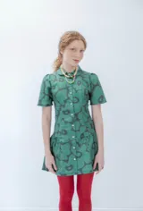 Vestido corto verde con estampado de flores negras, cuello camisero, mangas cortas abullonadas y falda con volantes.