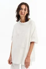Remera blanca de jersey de algodón peruano, de calce oversize, con escote a la base y manga corta. Cuenta con parche de tela bordado a tono en el frente.