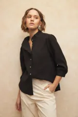 Camisa de manga tres cuartos color claro, con cuello alto con volados y botones de nácar.