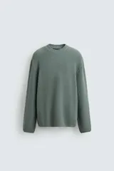 Sweater verde de punto con textura, corte holgado, cuello redondo y mangas largas con terminaciones en rib.