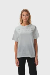 Remera gris claro con cuello redondo y bordados florales en el cuello y las mangas.