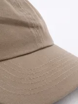 Gorra beige con paneles frontales rígidos y paneles traseros de malla.