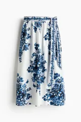 Pollera midi de corte holgado en popelina de algodón con estampado floral en tonos azules. Tiene tiro alto, tira ancha en un lateral y cierre oculto.