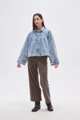 Campera de jean celeste con efecto lavado, caracterizada por mangas abullonadas y frunces en la zona del canesú, cierre frontal con botones metálicos y cuello camisero.