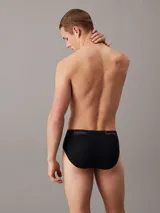 Pack de tres slips negros de algodón con cintura elástica con logo de Calvin Klein en blanco y rojo.