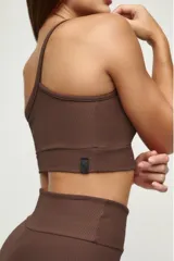 Top deportivo negro de un solo hombro, con textura acanalada y calce ajustado.