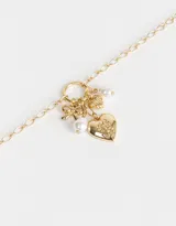 Collar dorado con cadena de eslabones y dijes colgantes: corazón con diseño floral, moño, perla y dije con forma de hoja.