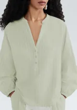 Blusa verde claro a rayas verticales, con cuello en V y cierre frontal con botones. Mangas 3/4 abullonadas y corte holgado.