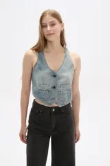 Chaleco de jean celeste sin mangas, con cuello en V, cierre frontal con botones y dos bolsillos con solapa en el pecho.