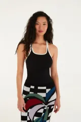 Musculosa negra con tirantes finos y ribete blanco, escote recto y corte ajustado.