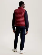 Chaleco acolchado rojo con cierre de cremallera, cuello alto y dos bolsillos laterales con cremallera. Tiene logo de Tommy Hilfiger bordado en el pecho.