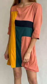 Vestido corto color salmón con bloques de color amarillo, verde y negro. Tiene cuello redondo y mangas 3/4.