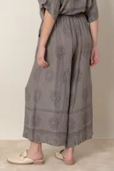 Pantalón palazzo de lino color crudo con estampado floral al tono, tiro alto y cintura elastizada.