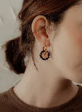 Aros colgantes dorados con forma de argolla, decorados con cuentas de cristal negras y ámbar.