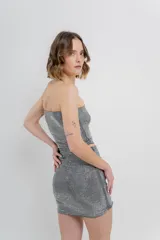 Minifalda negra ajustada al cuerpo, confeccionada en tejido elástico con strass plateado.