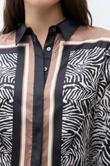 Camisa de manga larga con cuello camisero, estampado de cebra y detalles verticales en tonos negro, marrón y beige en el frente.