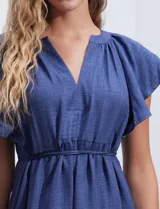 Vestido midi celeste de poliéster, con cuello a la base y escote en V. Presenta cintura con frunces y lazo de ajuste, mangas ranglan con sisa amplia y falda escalonada. Marca Emma & Michele.