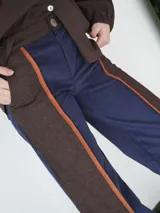 Pantalón de paño combinado con tira de cuero color naranja en los laterales.