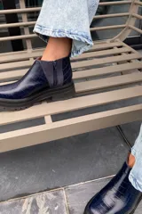 Bota de cuero azul con diseño de textura de cocodrilo, con cierre lateral y suela gruesa.