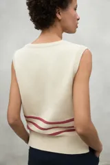 Chaleco de punto color crudo con cuello en V y tres rayas horizontales negras en el pecho.